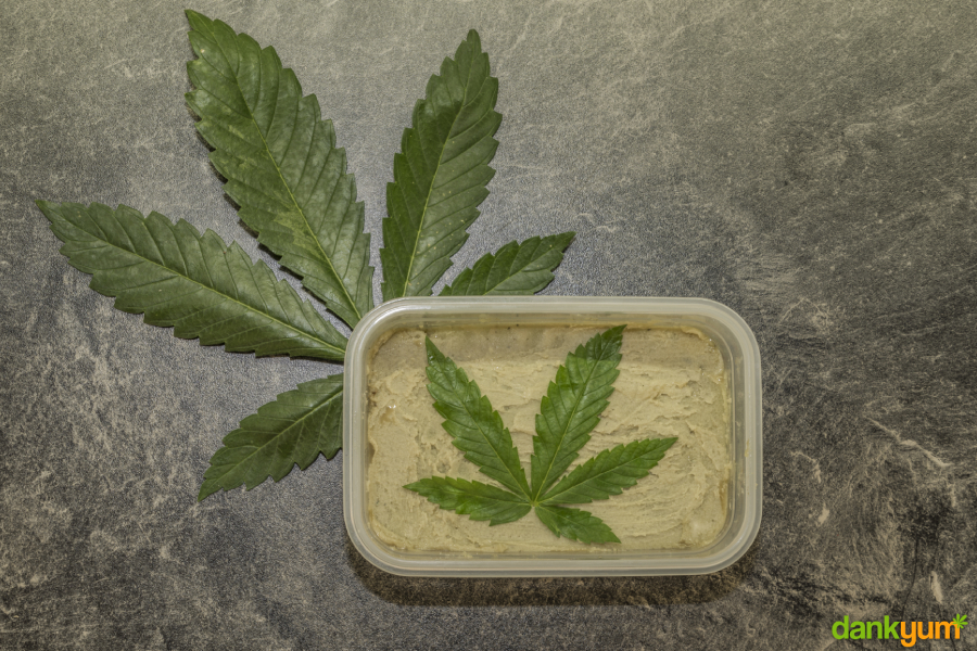 Cannabutter in a plastic container with a leaf on it